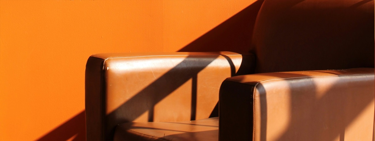 Brown leather armchair in front of orange wall