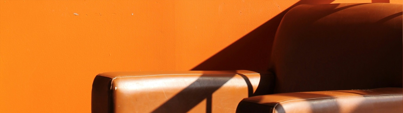 Brown leather armchair in front of orange wall